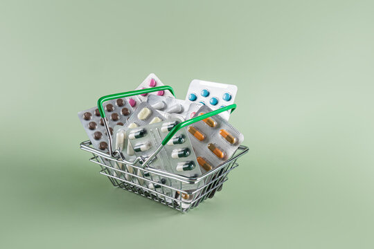 Basket of various pills and capsules on green background