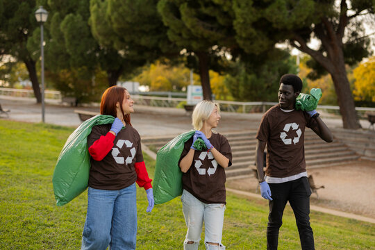 Multiracial friends cleaning the park during sunset