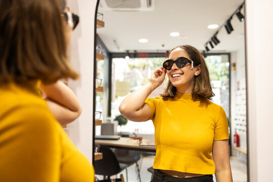 Woman trying on glasses in an optical store mirror
