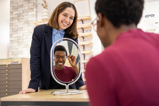 Customer trying on glasses with help in optical store