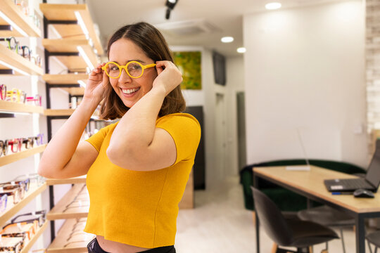 Young woman trying on glasses in optical store