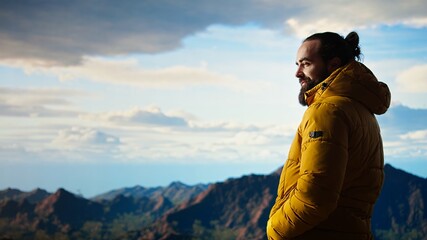 Alone traveler stands on a mountain summit soaking in the stunning view of peaks, clouds and endless sky, adventure seeker. Breathtaking scenery symbolizes determination. Camera A. © DC Studio