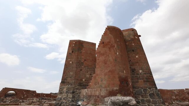 Discover the majestic ruins of Dashtadem Fortress in Armenia. The video showcases the medieval architecture, prominent red tuff stone walls, and a beautiful ancient archway against cloudy skies.

