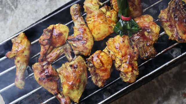 Close-up of a chef basting fresh grilled fish with traditional herbs brush on a charcoal grill, creating delicious smoky street food with authentic spice marination.
