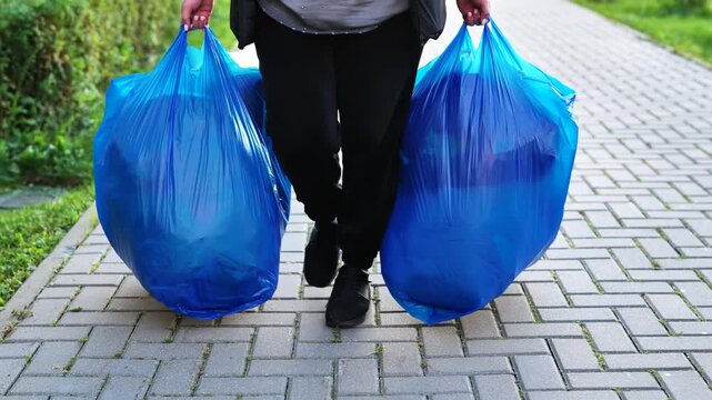 Woman carrying two large blue bags filled with charity donations for children