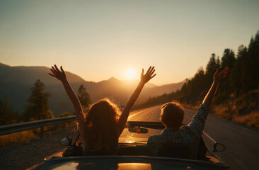 Fototapeta premium Two people sitting on the roof of a car with arms raised enjoying a sunset in a scenic mountain landscape