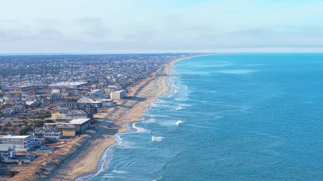 Kill Devil Hills, North Carolina, aerial cinematic video of the Atlantic coastline featuring sandy beaches, vacation homes, and the expansive Outer Banks landscape.