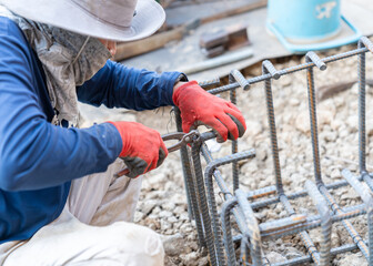 A construction worker using pliers to tie rebar steel wire.