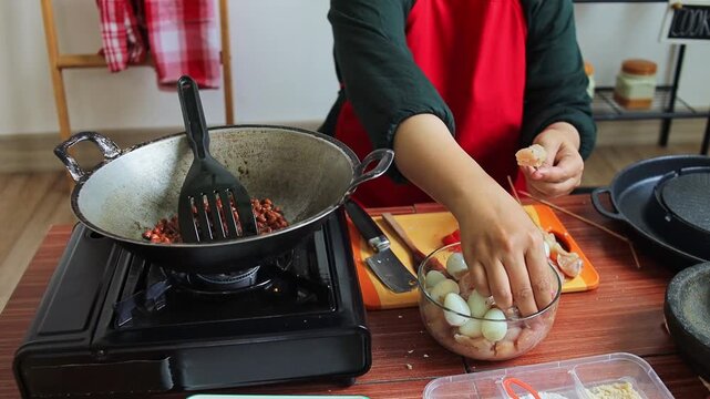 Close up of Hands home cooking preparing chicken satay skewers with quail eggs on wooden table