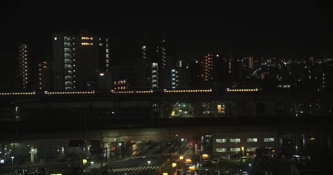 Glowing, silhouetted Japanese train moving through city at night
