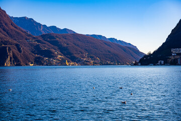 Obraz premium Calm lake with mountain village on the shore in Lugano