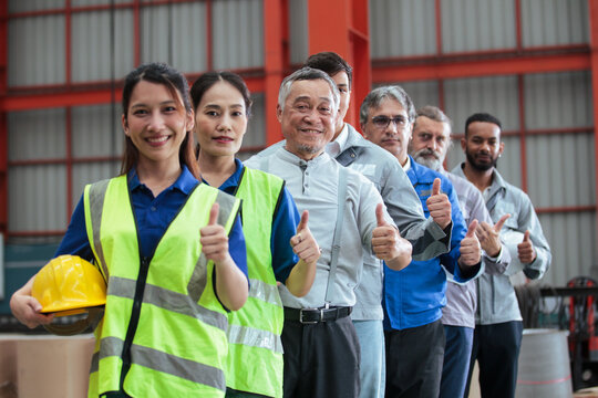 Diverse industrial workers team showing thumbs up in factory
