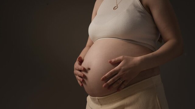 Maternity portrait of unrecognizable pregnant woman gently touching her belly, symbolizing motherhood, connection and new life
