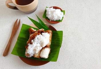 Traditional Indonesian kue putu served on banana leaf with grated coconut and palm sugar sauce. Popular as takjil or sweet snack for iftar during Ramadan. Authentic Southeast Asian dessert