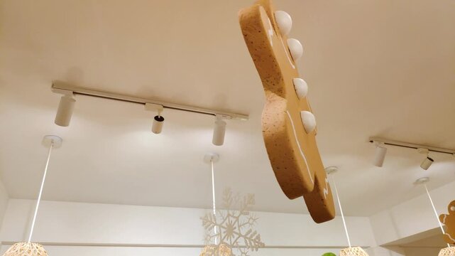A large hanging gingerbread man and golden paper star lantern decoration creates a festive Christmas atmosphere in a cafe.
