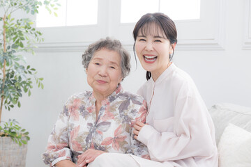 孫と高齢の祖母の笑顔の寄り添うクローズアップ　介護や親子のイメージのカメラ目線