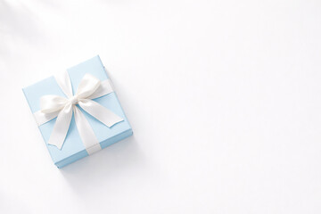 Elegant Blue Gift Box with White Ribbon on Clean Background Copy Space、白背景にブルーのギフトボックスと白リボン 高級感のあるプレゼントイメージ 余白あり