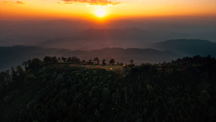 Fototapeta premium Aerial view of glowing camping tents on a remote mountain ridge at sunset.