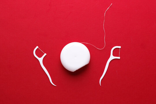 Dental floss and toothpicks on red background. Dental hygiene concept. Top view