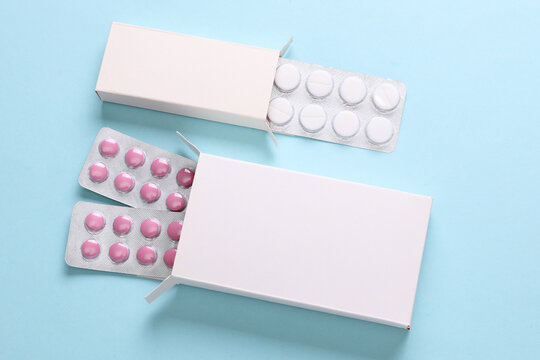 Blisters pack of pills with blank white boxes on blue background. Medicines, medical concept. Design mockup. Creative layout. Flat lay.