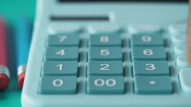 Person pressing numbers on light blue calculator keypad close up slow motion