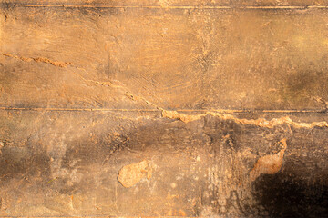 Detailed view of an aged and cracked stone or concrete surface with warm earth tones, showing natural wear, erosion, and organic textures perfect for abstract backgrounds and design projects