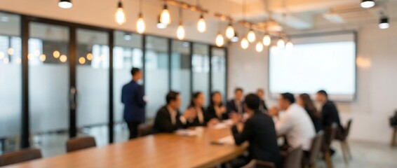 Fototapeta premium A blurred image captures a diverse group of business professionals around a large conference table in a modern meeting room.