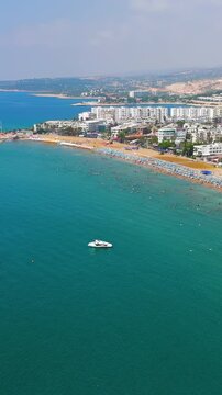 Vertical video. Kizkalesi, Mersin, Turkey. Scenic beach with umbrellas and Maiden Castle island view, aerial perspective of Korykos Castle on coastline.. Aerial View, Departure of the camera. Rich co