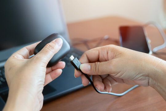 Woman holds black charging case with headphones and USB-C, black cable for charging