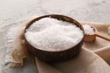 Bowl with sea salt, scoop and napkin on grunge background