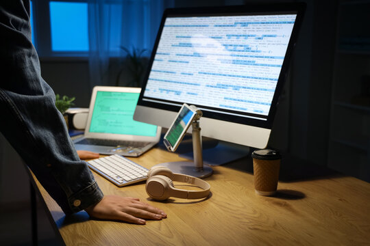 Male programmer near table with modern computer and laptop in office, closeup