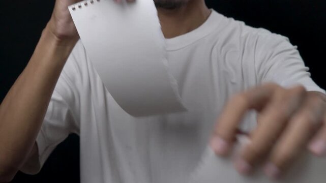 Close-up image of a man tearing a sheet of paper with his hands