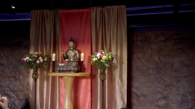 Peaceful Buddha statue with flowers and candles indoor setting