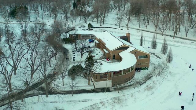 drone overlooking restaurant robin des bois in park lafointaine montreal, quebec, canada in winter n some people doing patin