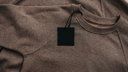 Brown crewneck sweatshirt with a blank black tag, showcasing cozy fabric texture and stitching details © shine.graphics