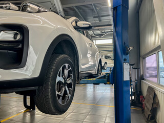 Car undergoing maintenance on a hydraulic lift in a modern auto repair workshop