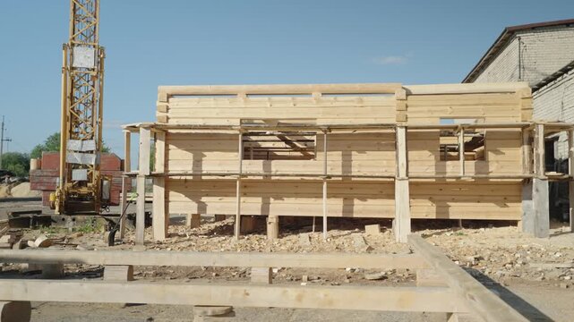 Unfinished house and wooden beams next to a construction crane