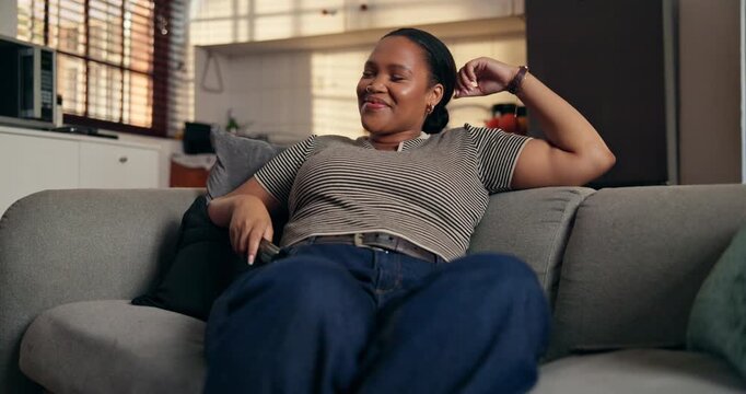 Laughing, woman and watching tv with remote, lounge and streaming comedy with subscription in house. Happy, black person and relax with controller for entertainment, funny movie and humor in home