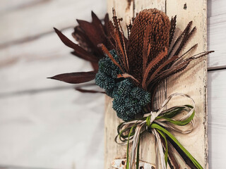 アンティーク調の白いウッドパネルに飾られたワイルドフラワーのスワッグ