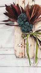アンティーク調の白いウッドパネルに飾られたワイルドフラワーのスワッグ