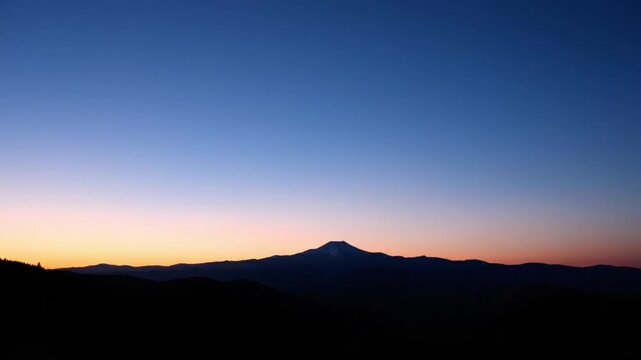Silhouette of a mountain range at sunset with a gradient blue and orange sky