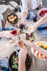 Friends raising glasses toasting at outdoor celebration dinner © Cavan