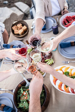 Friends raising glasses toasting at outdoor celebration dinner