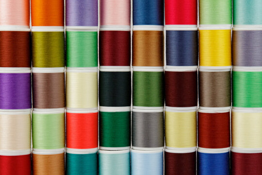 Colored spools of thread in an orderly row.
