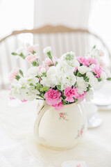 Pink and white carnations decorate a table in a charming floral vase