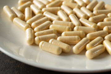 A closeup view of a pile of ginger supplement capsules, on a plate.