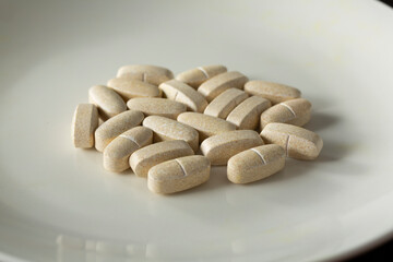 A view of a pile of vitamin tablets, on a plate.