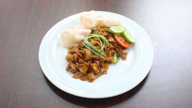 Authentic Indonesian Fried Kwetiau Served With Crispy Crackers and Fresh Garnish