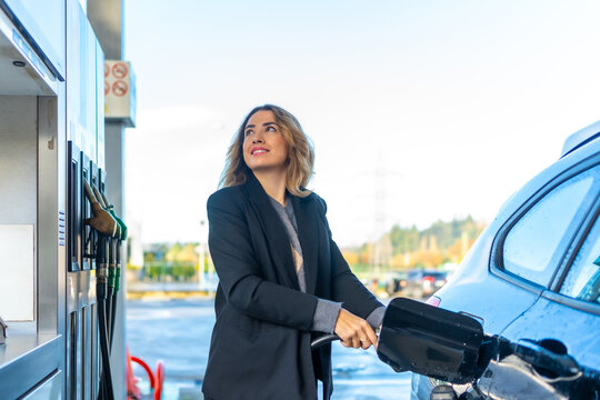 Woman refueling car with gasoline at gas station