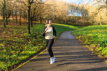 Fototapeta premium Woman jogging in park enjoying autumn fitness run